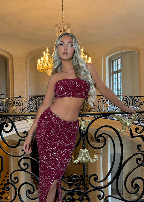 Women's embellished burgundy two-piece set. Bandeau crop top fully embellished in hot fix and matching burgundy maxi skirt with thigh high slit.